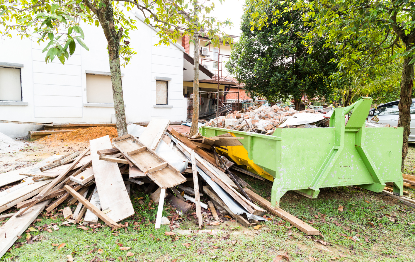 A green dumpster overflowing with junk and construction waste