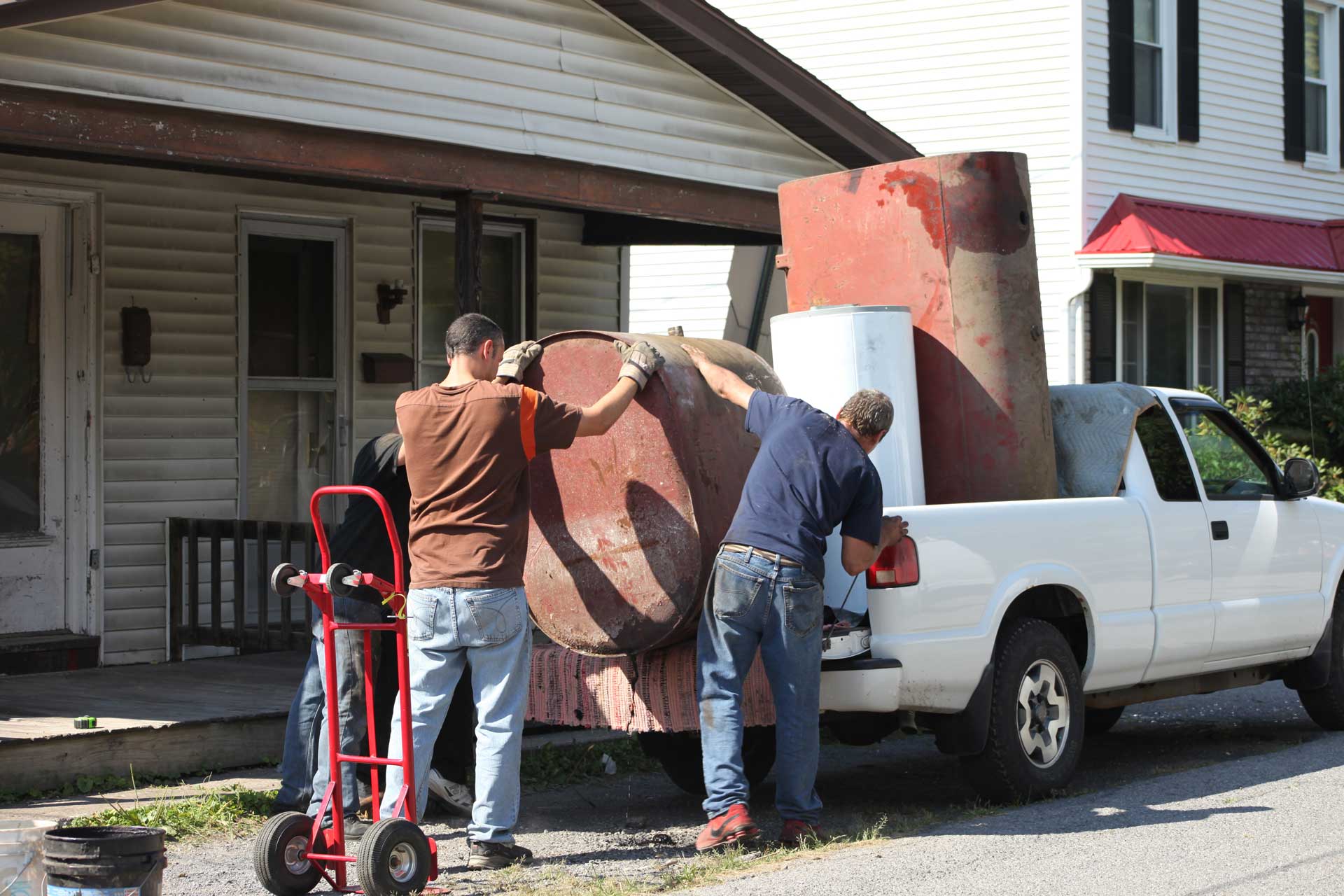 Two men loading old furniture and a water heater on to the back of a truck